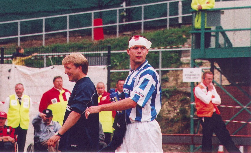 Mathew Wicks is looks on as he is lead away to receive stitches in a head wound, Torquay 02 September 2000